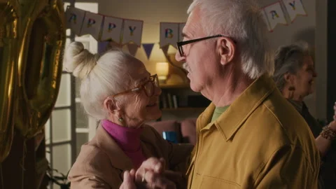 Happy 70-Year-Old Lady Dancing and Talking with Elderly Friend at Birthday Party 動画素材 319261413