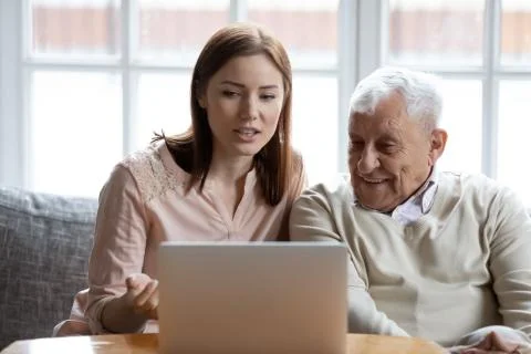Happy 70s man learning using computer software with caring daughter. Foto stock