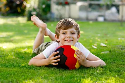Happy active kid boy playing soccer with ball in German flag colors. Healthy Stock Photos