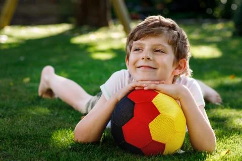 Happy active kid boy playing soccer with ball in German flag colors. Healthy Stock Photos