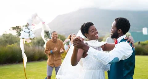 Happy african american couple holding hands and dancing during wedding Stock Photos