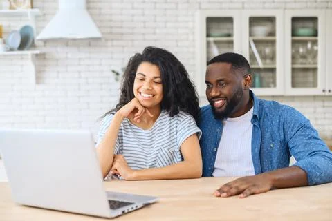 Happy African-American couple spends leisure time with the laptop Stock Photos