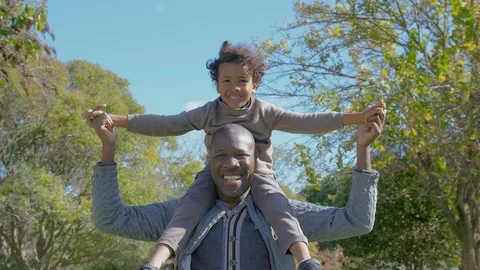 Happy African American dad carrying adorable son on shoulders Stock Footage