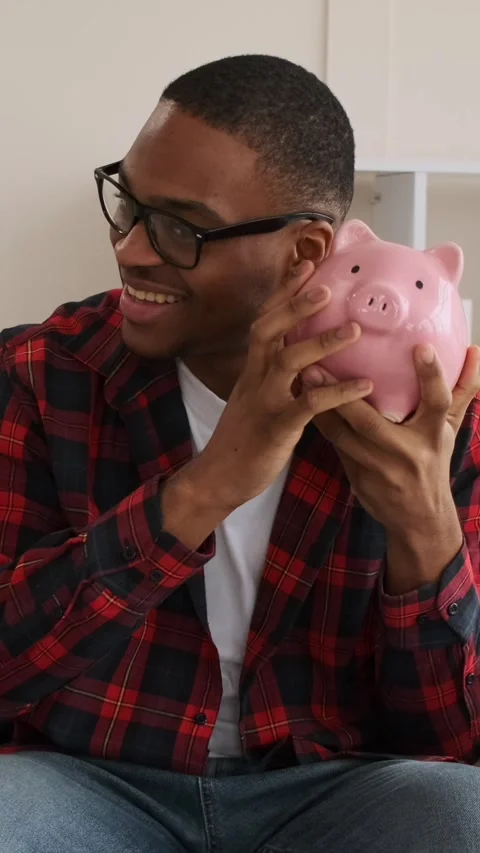 Happy African American Man Saving Money in a Piggy Bank Stock Footage 328126568