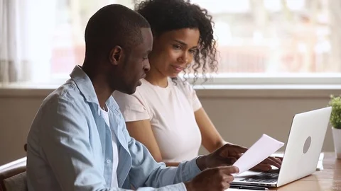 Happy african american young couple paying bills online at home Stock Footage