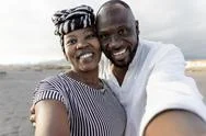 Happy African Couple Taking Selfie On The Beach With Mobile Smartphone Camera Stock Photos