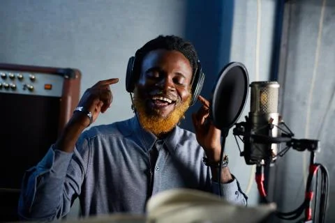 Happy African man singing and recording his songs in studio Stock Photos