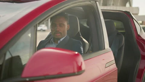 Happy african man sitting inside his new electric car while taking keys from Stock Footage 156253530