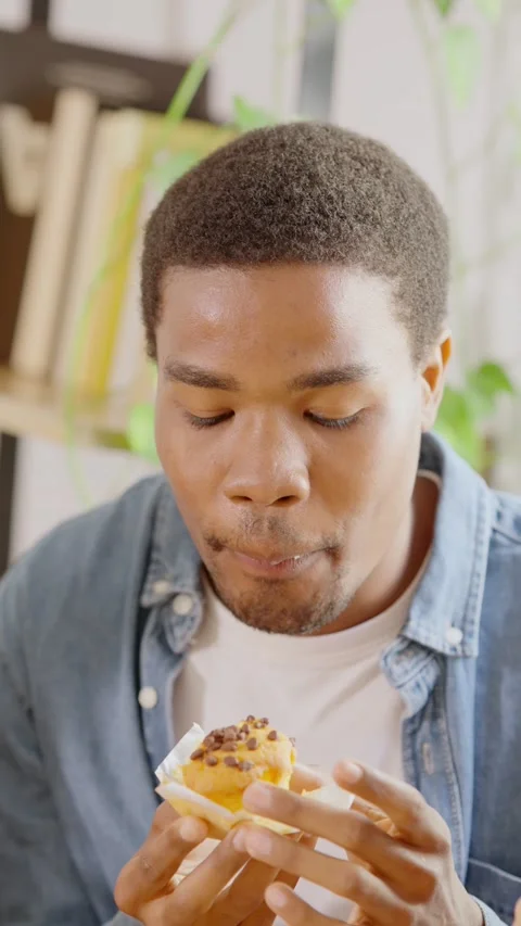 Happy african man smiling while eating a cupcake Stock Footage 239217829