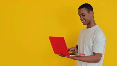 Happy african student man using laptop computer over yellow background Stock Footage 271669915