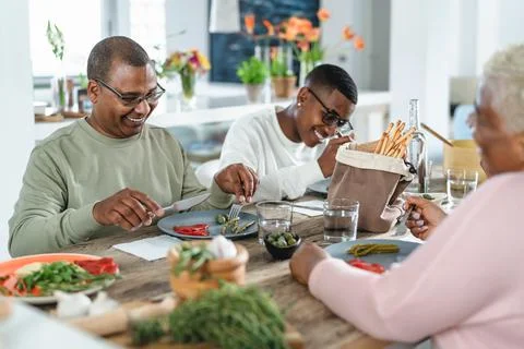 Happy afro Latin family eating healthy lunch with fresh vegetables at home Stock Photos
