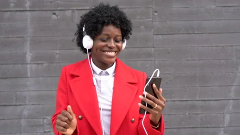 Happy afro woman dancing while enjoying listening to music with headphones Stock Footage 164038393