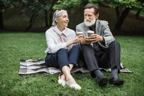 Happy aged couple drinking coffee while relaxing at park Stock Photos