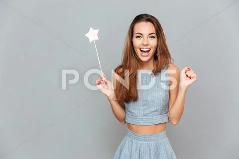 Happy amazed young woman holding magic wand Stock Photos