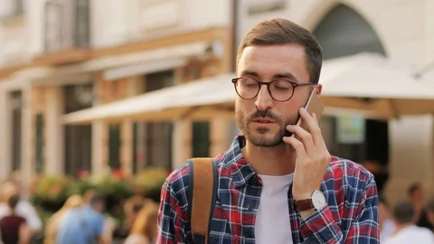 A happy and handsome young man walking around the town talking on the phone and Stock Footage 81049948