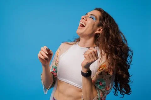 Happy and radiant non-binary stylish person with very long hair on blue bac.. Stock Photos