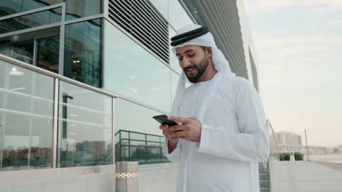 Happy Arab man in Kandoora using cell phone device Arabic Emirati local at Stock Footage 222769183