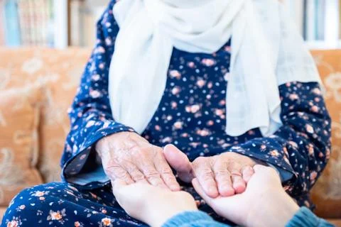 Happy arabic muslim granddaughter holding her grandmother hands Stock Photos