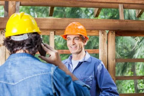 Happy Architect Looking At Colleague Using Cellphone Stock Photos