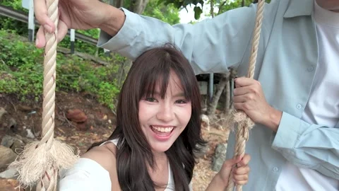 Happy Asian Couple Having Fun on Rope Swing Outdoors Stock Footage 346693290