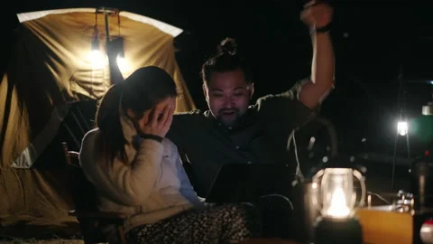 Happy Asian couple using a smartphone while camping at night Video stock 168484524