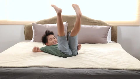 Happy asian elementary school boy jumping on bed and have fun dancing, kid .. Stock Footage 249492960