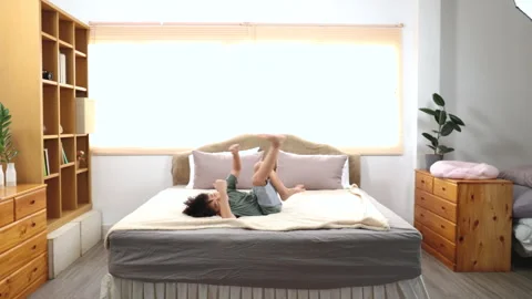 Happy asian elementary school boy jumping on bed and have fun dancing, kid .. Stock Footage 249505608