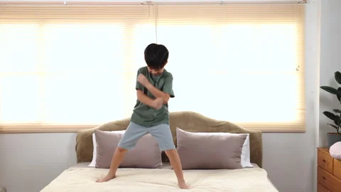 Happy asian elementary school boy jumping and dancing on bed, kid jumped an.. Stock Footage 249506035