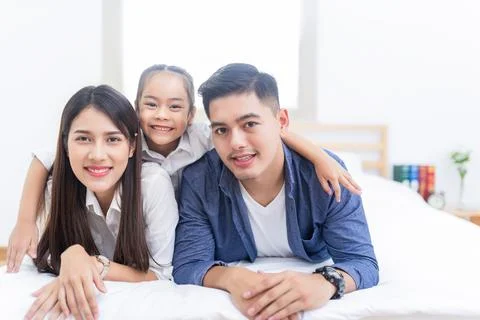 Happy asian family lying on a bed Stock Photos