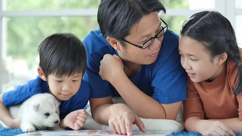 Happy Asian family reading book at home slow motion Stock Footage
