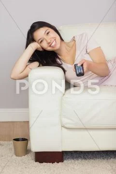 Happy asian girl lying on the sofa watching tv Stock-Fotos