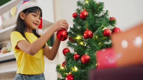 Happy asian a little girl decorating the Christmas tree at home. Merry Christmas Stock Photos