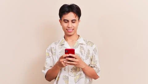 Happy Asian man smiling while typing on smartphone for mobile chat applicat.. Stock Photos
