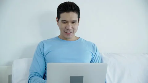 Happy Asian man using notebook Or laptop to work in room at home. Talk to people Stock Footage 140447546