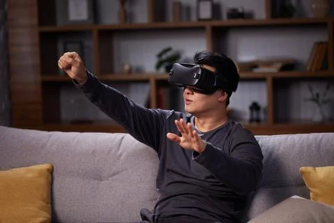 Happy Asian man using VR and playing video games at home. Joyful man using Stock Photos