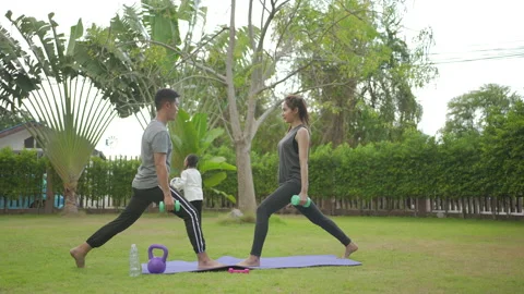 Happy asian parent doing exercise while kid doing football exercises Video stock 146692073