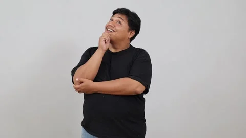 Happy Asian plus size man in black shirt looking up with arms crossed, isolated Stock Footage 342475366