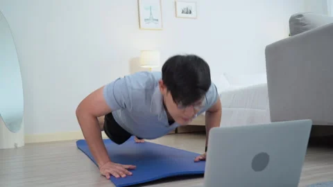 Happy asian young man doing exercise and watching tutorial on laptop with m.. 動画素材 252816565