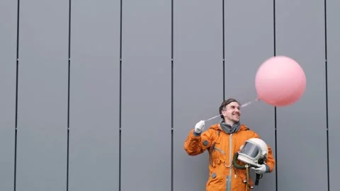 Happy astronaut wearing space suit with helmet holding pink helium balloon Stock Footage 262859778