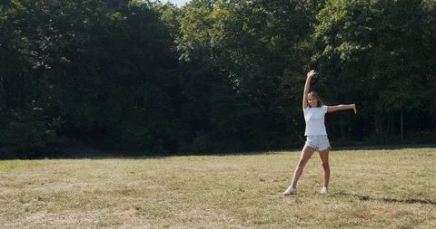 Happy atractive female does exercise somersault on meadow at summer. Slow motion Stock Footage 117212874