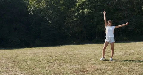 Happy atractive female does exercise somersault on meadow at summer. Slow motion Stock Footage 117364972