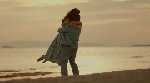 Happy attractive couple dancing at the beach at sunset,slow motion Stock Footage