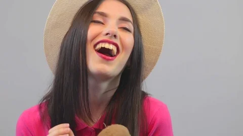 Happy attractive model shows a coconut. Pink polo and hat on a white background Stock Footage 73569340