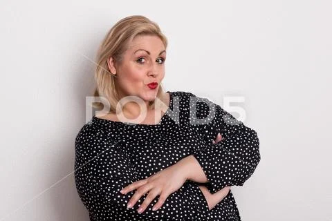 A happy attractive overweight woman in studio pouting lips. Stock Photos