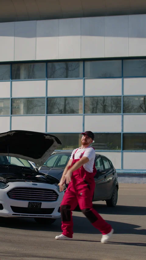 Happy auto mechanic dancing joyfully in vibrant workshop during break Stock Footage 320958876