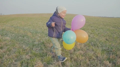 Happy baby boy, fun running around with balloons. Outdoor recreation. In Evening Видео 106947500