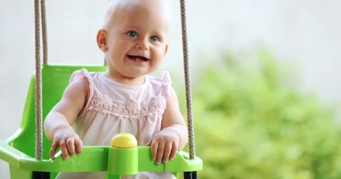 Happy baby enjoying outdoor activities and smiling while swinging Stock Footage
