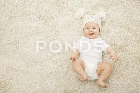 Happy Baby in Hat and Diaper Lying on Carpet Background, Smiling Infant Kid Stock Photos