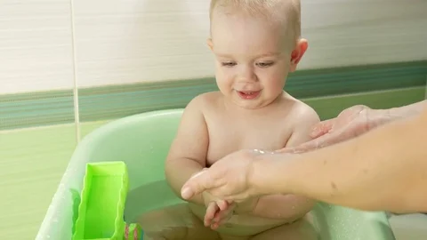 Happy baby taking a bath playing with foam bubbles. Mother washing little boy Stock Footage 71821446