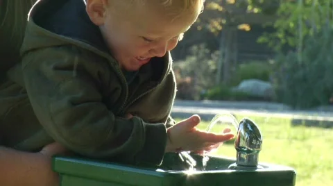Happy baby with water fountain in sunlight Stock Footage